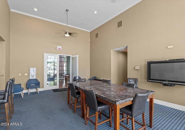 carpeted dining room with ceiling fan, crown molding, and a high ceiling