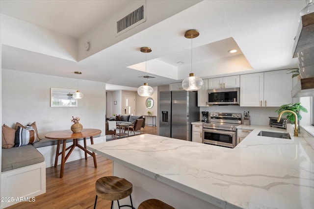 6271 E Evans Dr, Scottsdale, AZ 85254 - kitchen featuring a peninsula, visible vents, a sink, stainless steel appliances, and a raised ceiling