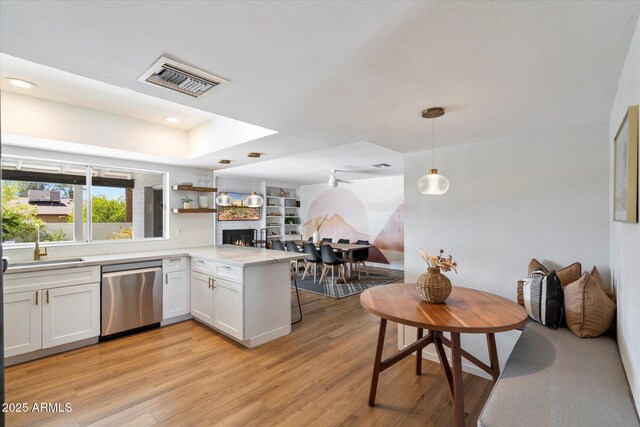 6271 E Evans Dr, Scottsdale, AZ 85254 - kitchen with a peninsula, a warm lit fireplace, visible vents, dishwasher, and a sink
