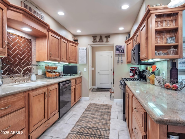 kitchen featuring light stone countertops, sink, decorative backsplash, and black appliances