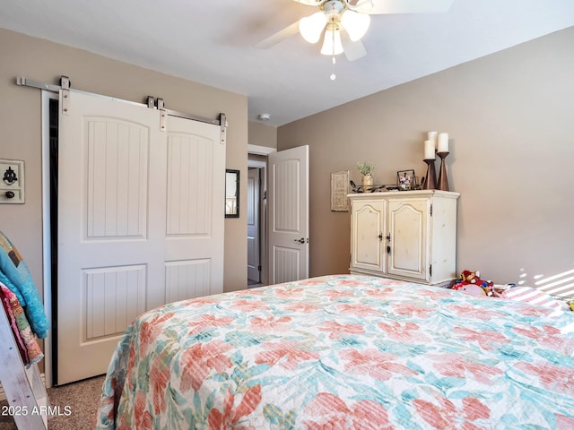 bedroom with ceiling fan and a barn door