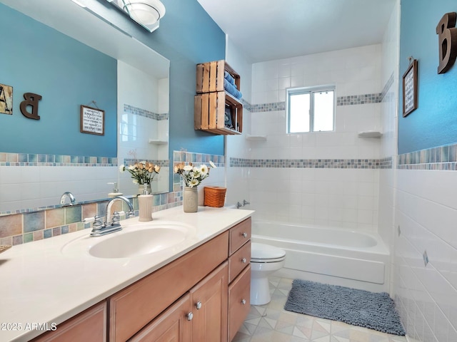 full bathroom featuring vanity, tiled shower / bath, tile walls, and toilet