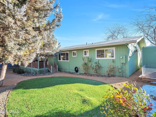 rear view of house featuring a wooden deck and a lawn