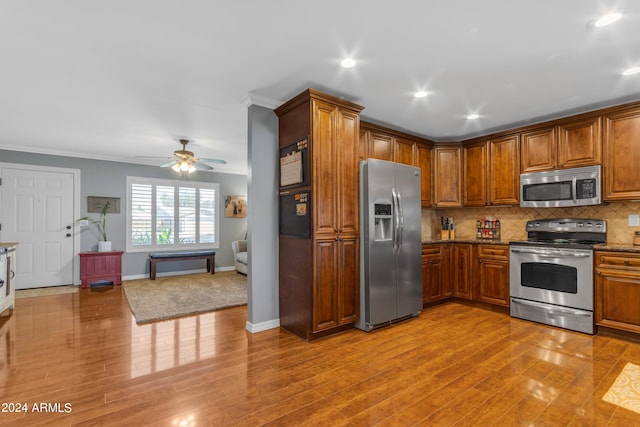 kitchen with crown molding, appliances with stainless steel finishes, backsplash, and brown cabinets