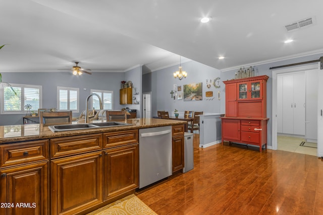 kitchen featuring a barn door, visible vents, dishwasher, decorative light fixtures, and a sink