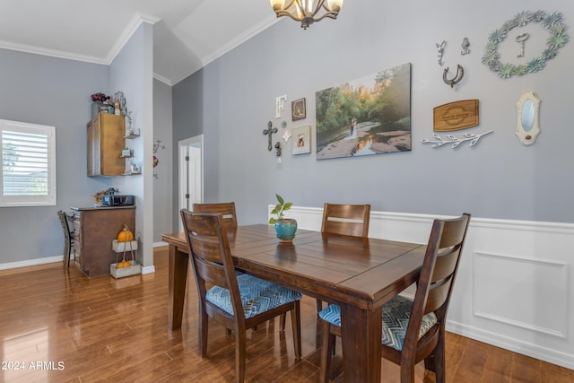 dining room featuring a wainscoted wall, ornamental molding, wood finished floors, and a notable chandelier