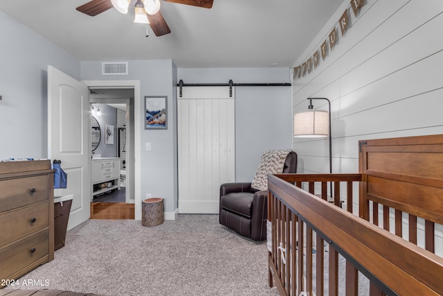 bedroom featuring a barn door, light colored carpet, a ceiling fan, visible vents, and a closet