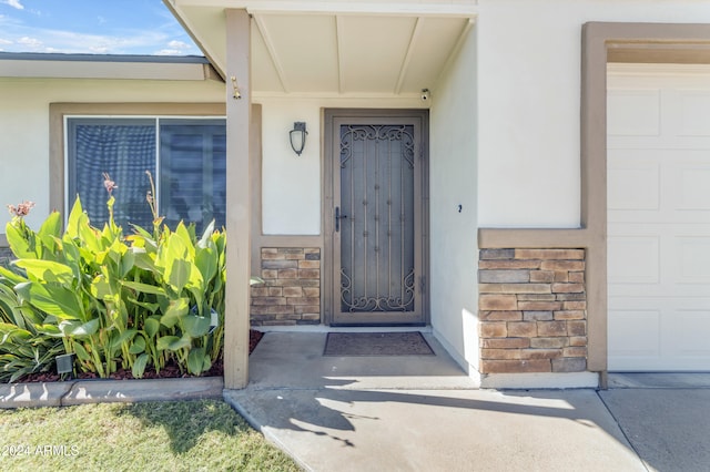 doorway to property featuring stone siding and stucco siding