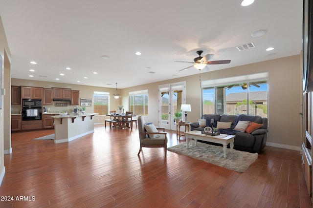 living room featuring wood finished floors, a wealth of natural light, ceiling fan, and visible vents