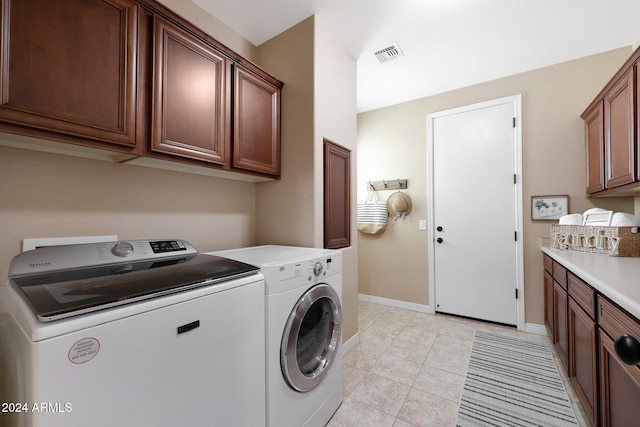 clothes washing area with visible vents, light tile patterned flooring, washer and dryer, baseboards, and cabinet space