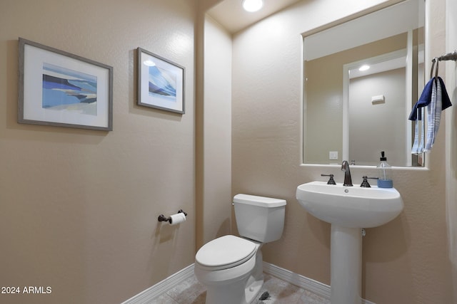 bathroom featuring toilet, sink, and tile patterned flooring