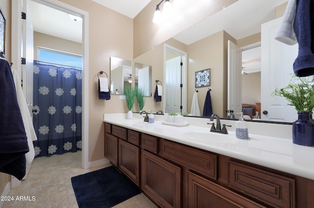 full bath featuring a sink, baseboards, a ceiling fan, and double vanity