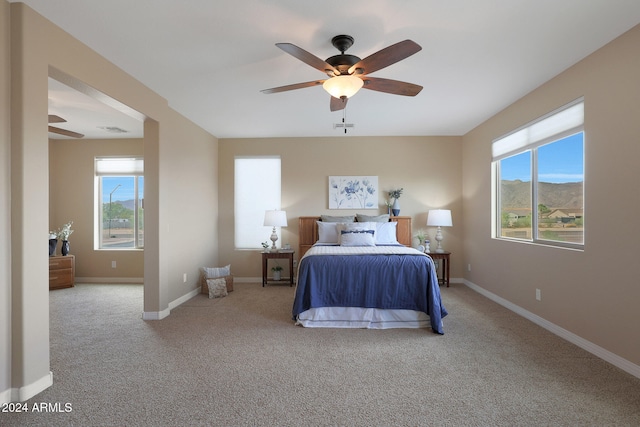 carpeted bedroom featuring a mountain view and ceiling fan