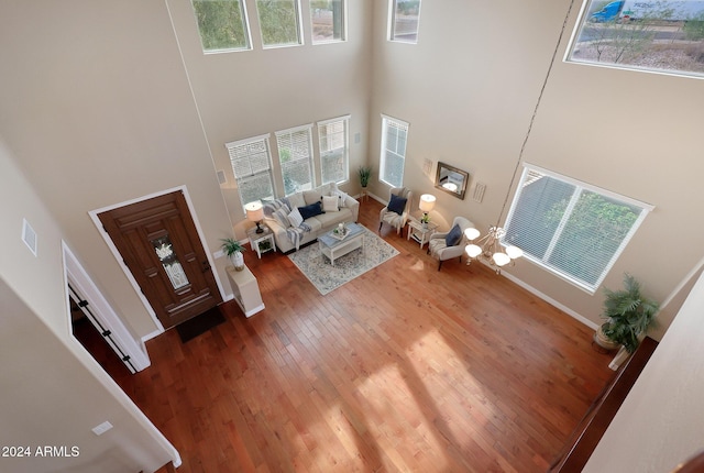 living room with a wealth of natural light, wood finished floors, and a towering ceiling