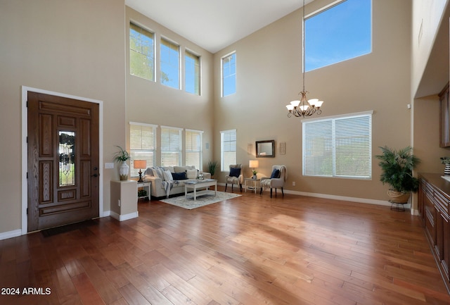 foyer with a towering ceiling, a notable chandelier, and hardwood / wood-style floors