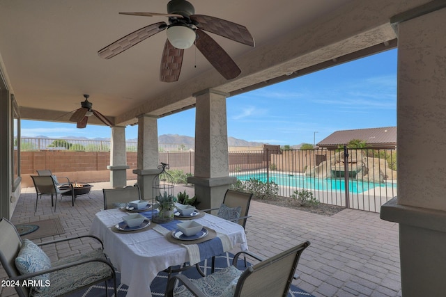 view of patio with ceiling fan, a mountain view, a fenced backyard, a fire pit, and outdoor dining space