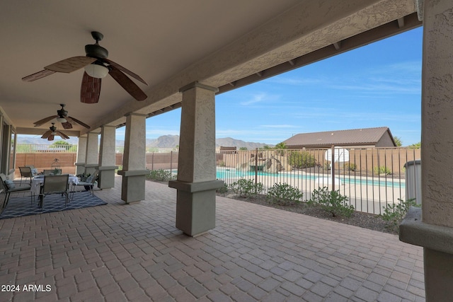 view of patio featuring ceiling fan, outdoor dining area, a fenced backyard, a fenced in pool, and a mountain view