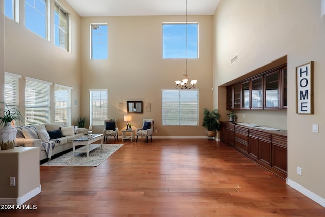 living room with light wood-style flooring, a high ceiling, and a chandelier