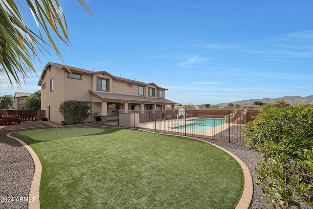 rear view of house featuring a fenced in pool, a mountain view, and a patio