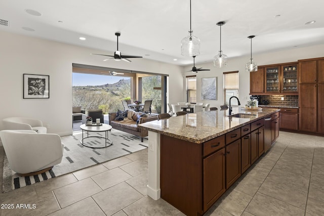 kitchen with open floor plan, a sink, light stone countertops, and decorative backsplash