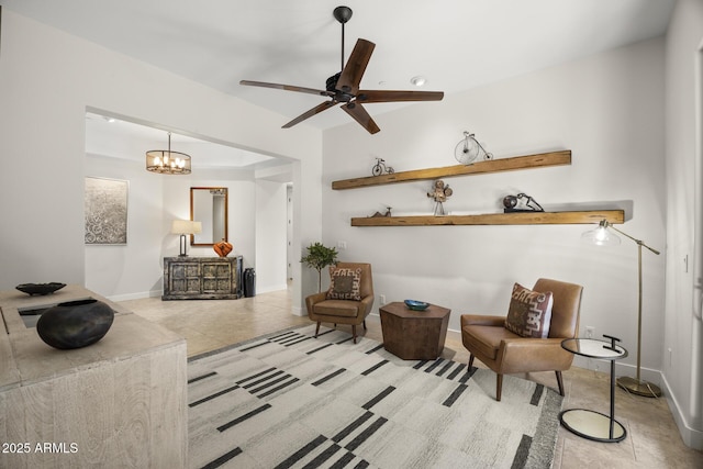 sitting room with baseboards, ceiling fan with notable chandelier, and tile patterned floors