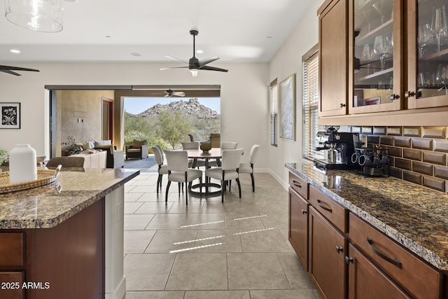 dining area featuring a ceiling fan, baseboards, and light tile patterned floors