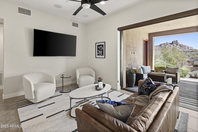 living room with a ceiling fan, visible vents, and baseboards