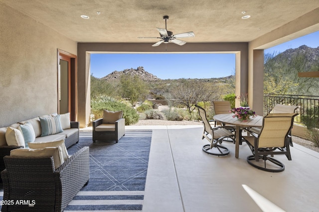 view of patio featuring a mountain view, outdoor dining space, an outdoor living space, and a ceiling fan