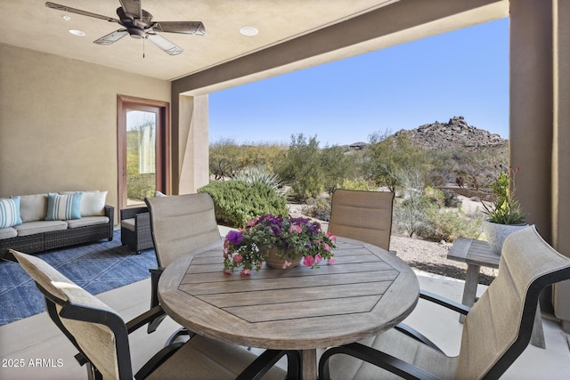 view of patio featuring ceiling fan, an outdoor living space, and a mountain view