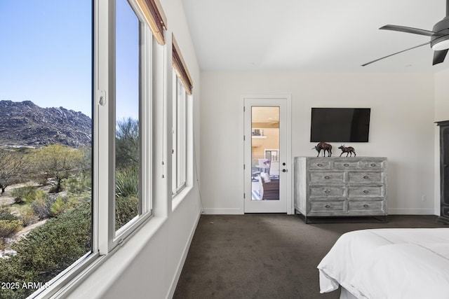 bedroom with baseboards, multiple windows, a mountain view, and dark colored carpet