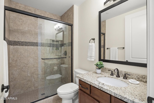 full bathroom featuring a shower stall, toilet, and vanity