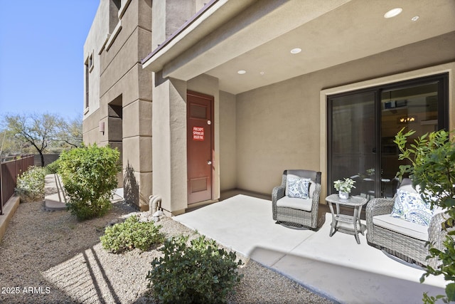 entrance to property with fence, a patio, and stucco siding