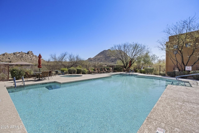 pool featuring a patio area, a mountain view, fence, and a community hot tub