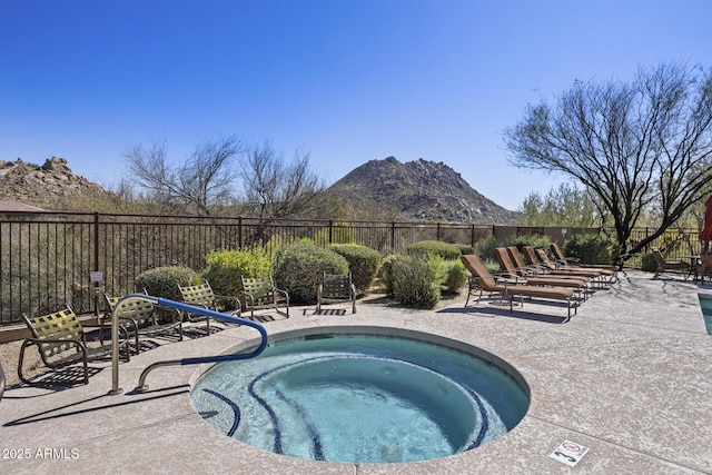 view of pool featuring a hot tub, fence, a mountain view, and a patio