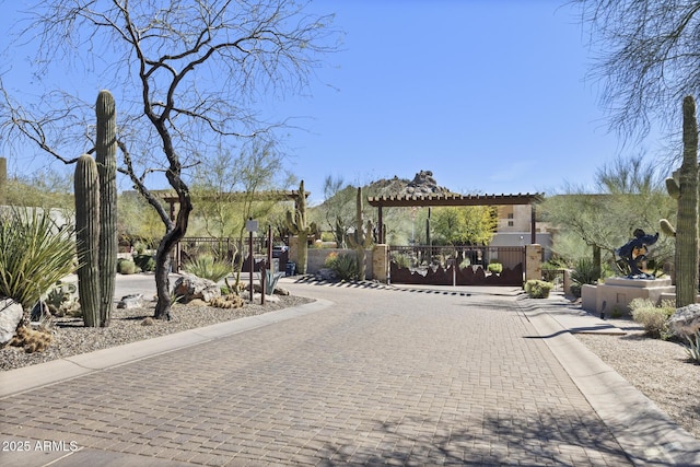 view of road with curbs, a gated entry, and a gate