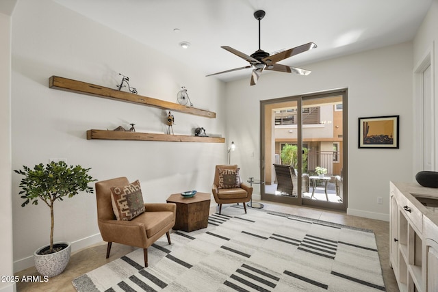 sitting room featuring ceiling fan and baseboards