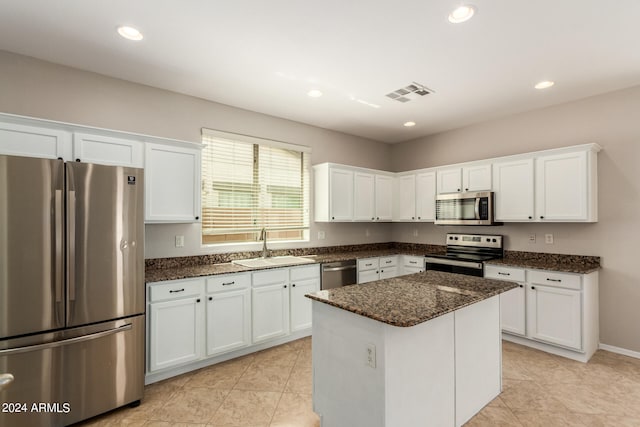 kitchen with white cabinets, stainless steel appliances, light tile patterned floors, and a kitchen island