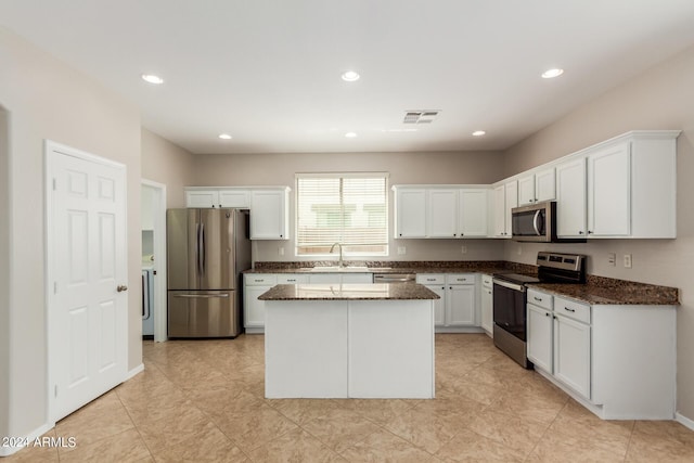 kitchen with visible vents, dark stone countertops, a center island, white cabinetry, and appliances with stainless steel finishes