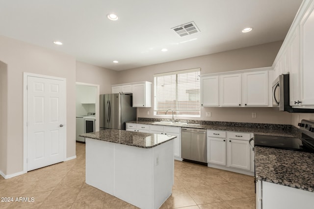 kitchen with light tile patterned floors, white cabinets, a center island, appliances with stainless steel finishes, and sink