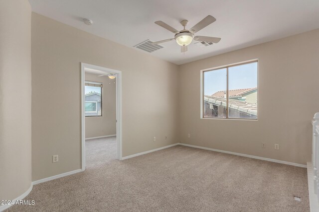 spare room with carpet, a wealth of natural light, and ceiling fan