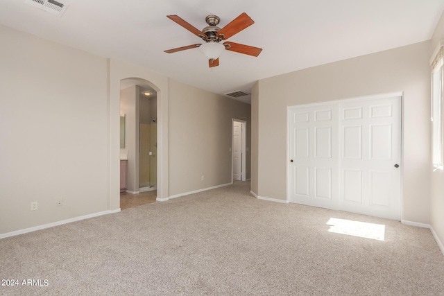 unfurnished bedroom featuring arched walkways, visible vents, light colored carpet, and baseboards