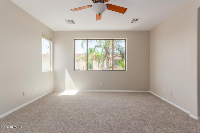 carpeted empty room featuring visible vents, ceiling fan, and baseboards