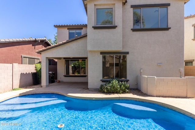 rear view of house featuring stucco siding, a tiled roof, a fenced in pool, and fence