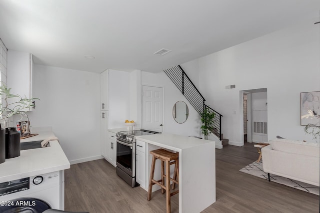 kitchen featuring a breakfast bar, white cabinetry, stainless steel range with electric cooktop, and dark wood-type flooring