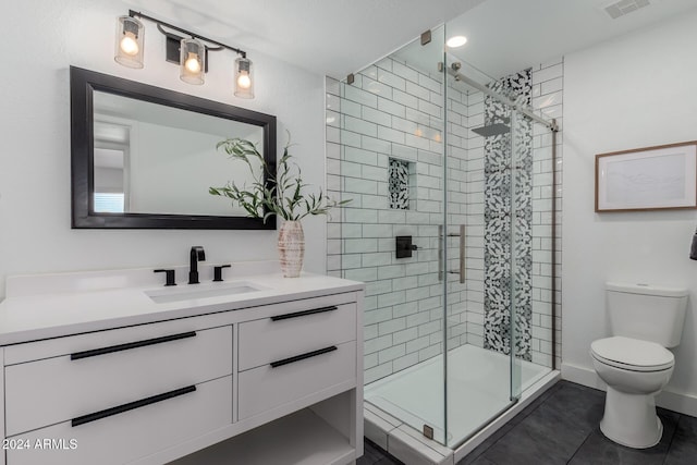 bathroom with tile patterned floors, vanity, a shower with shower door, and toilet