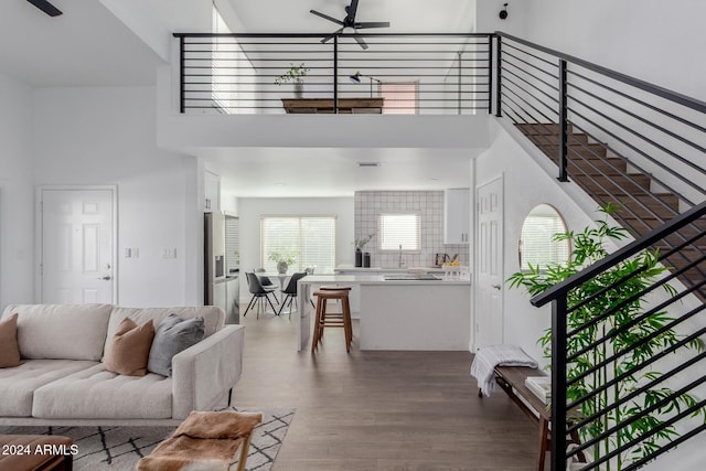 living room featuring ceiling fan, wood-type flooring, and a towering ceiling