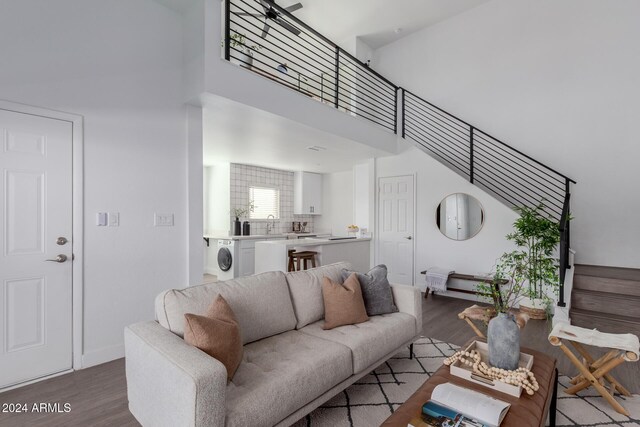 living room with washer / dryer, wood-type flooring, and a towering ceiling