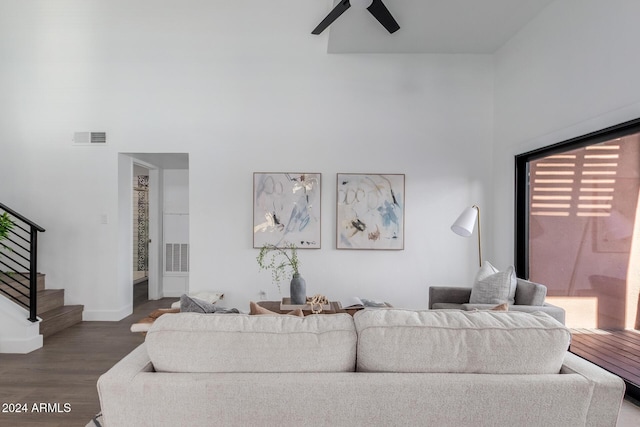 living room with ceiling fan, dark hardwood / wood-style flooring, and a high ceiling