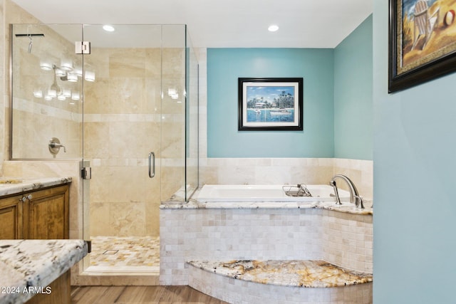 bathroom with independent shower and bath, vanity, and hardwood / wood-style floors