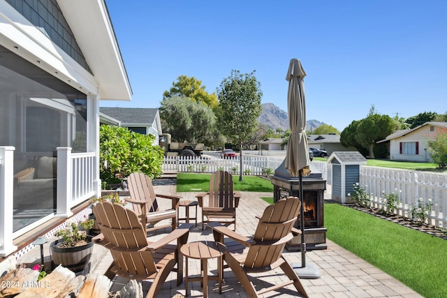 view of patio with a mountain view, a storage shed, a sunroom, and an outdoor fire pit